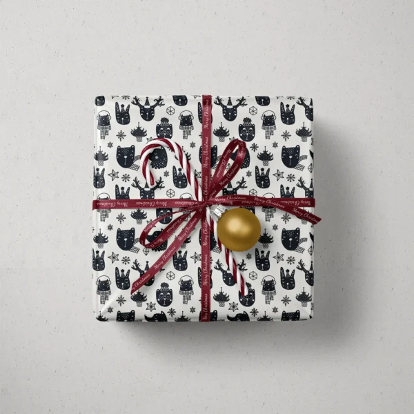 Top view of a gift in black and cream animal paper with a ribbon, a candy cane and a bauble