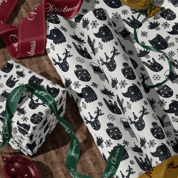 A sheet of black and cream animal gift wrap and a wrapped box with satin ribbons on a wooden floor