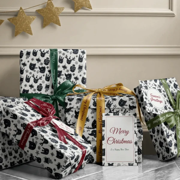 Stack of presents in black and cream animal paper with ribbons and a Merry Christmas card by a beige wall
