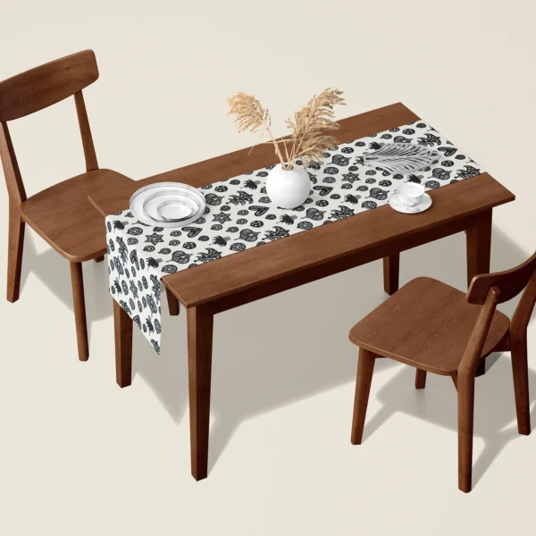 Black and cream Scandi ornament Christmas table runner on a walnut dining table with two wooden chairs