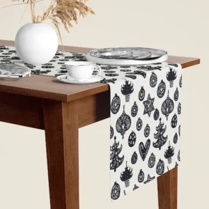 Black and cream Scandi ornament Christmas table runner hanging over the end of a walnut dining table, close-up