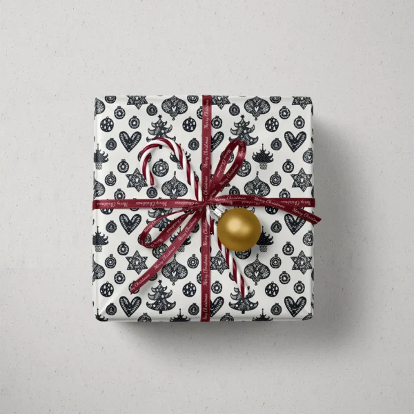 Top view of a gift in black and cream ornament paper with a ribbon, a candy cane and a bauble