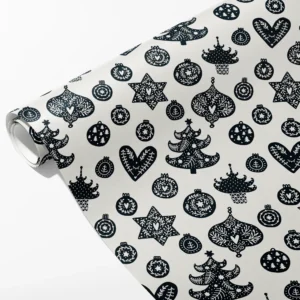Roll of cream wrapping paper with black folk baubles, hearts, stars and Christmas trees, partly unrolled on white