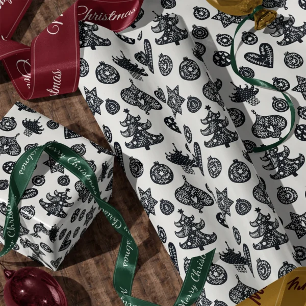 A sheet of black and cream ornament gift wrap and a wrapped box with satin ribbons on a wooden floor