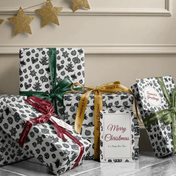 Stack of presents in black and cream ornament paper with ribbons and a Merry Christmas card by a beige wall