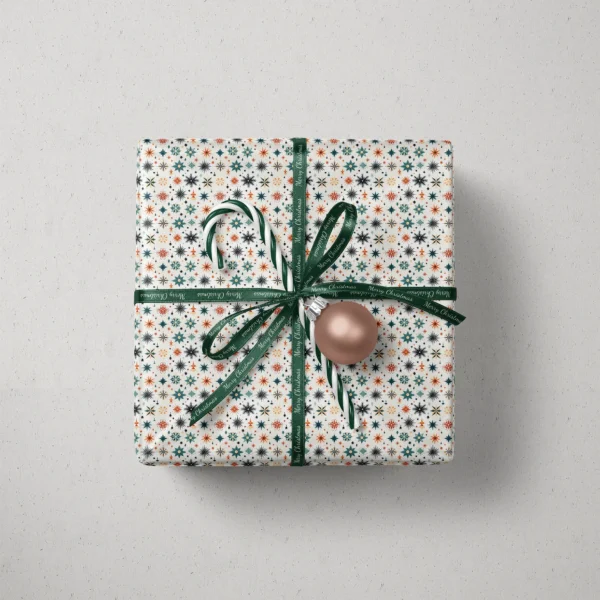 Top view of a gift in Scandi starburst paper with a ribbon, a candy cane and a bauble
