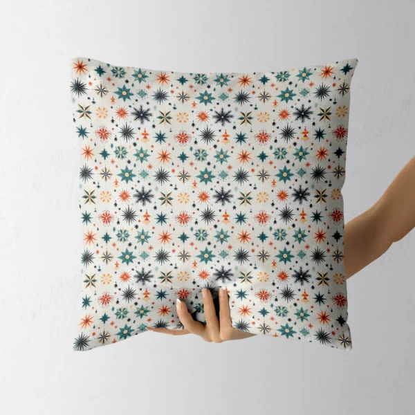 Hand holding the square off-white pillow with teal and rust stars