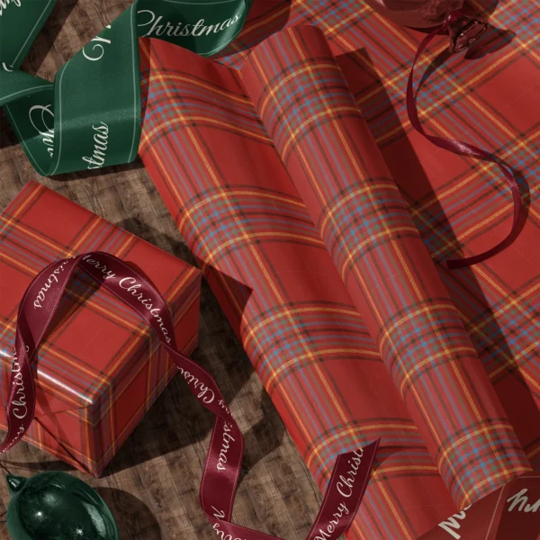 Rolls of scarlet multi-stripe plaid gift wrap and a wrapped box with satin ribbons on a wooden floor