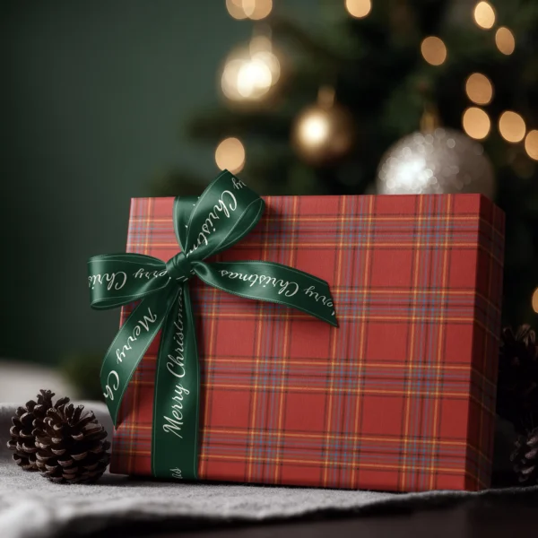 Box wrapped in scarlet multi-stripe plaid paper with a satin ribbon bow, Christmas tree lights behind