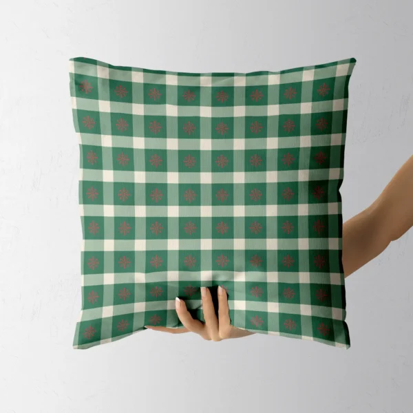 Hand holding the green and sage check pillow with red snowflakes