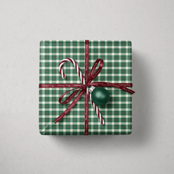 Top view of a gift in snowflake gingham paper with a ribbon, candy canes and a bauble