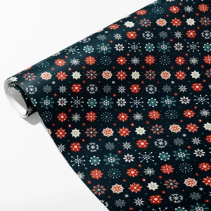 Roll of navy wrapping paper with rows of red, teal, cream and white snowflakes, partly unrolled on white