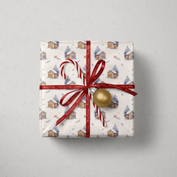 Top view of a gift in cream snowy cabin paper with a red ribbon, a candy cane and a gold bauble