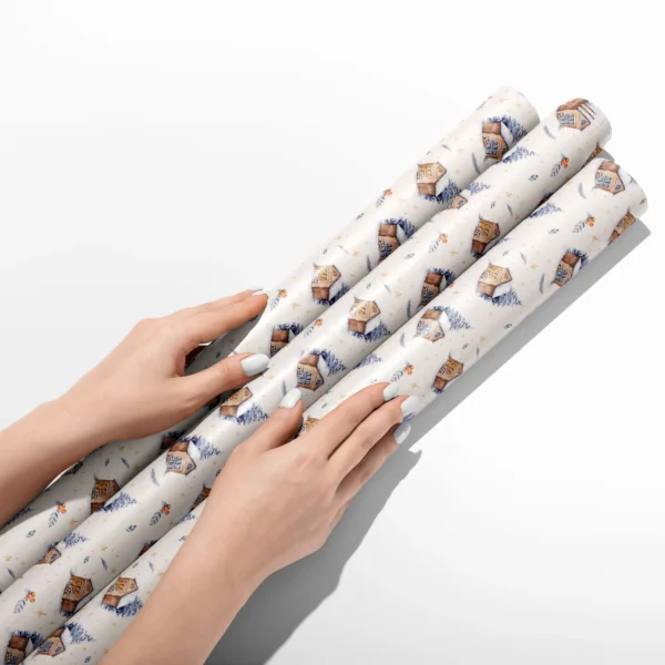 Hands smoothing three rolls of cream snowy cabin wrapping paper on a white table
