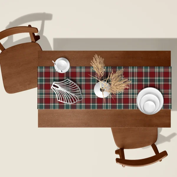 Burgundy and green tartan table runner seen from above on a walnut table with white dishes and dried pampas