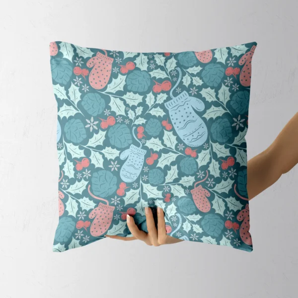 A hand lifting the teal pillow printed with pink and blue mittens