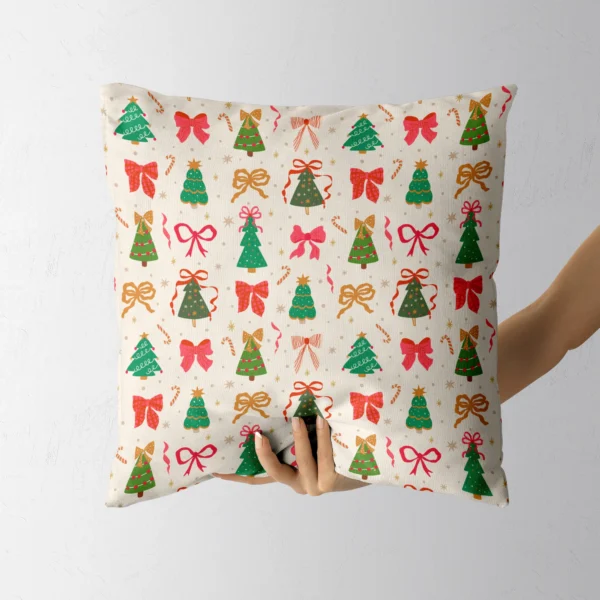 A hand holding the cream pillow with little trees and bows