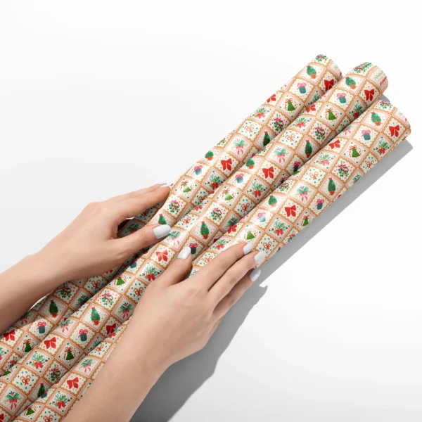 Hands smoothing three rolls of vintage gold tile wrapping paper on a white table