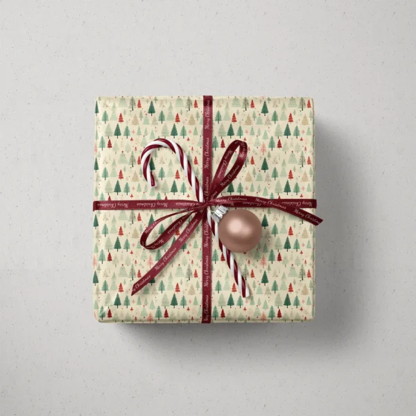 Top view of a gift in cream vintage forest paper with a ribbon, a candy cane and a bauble
