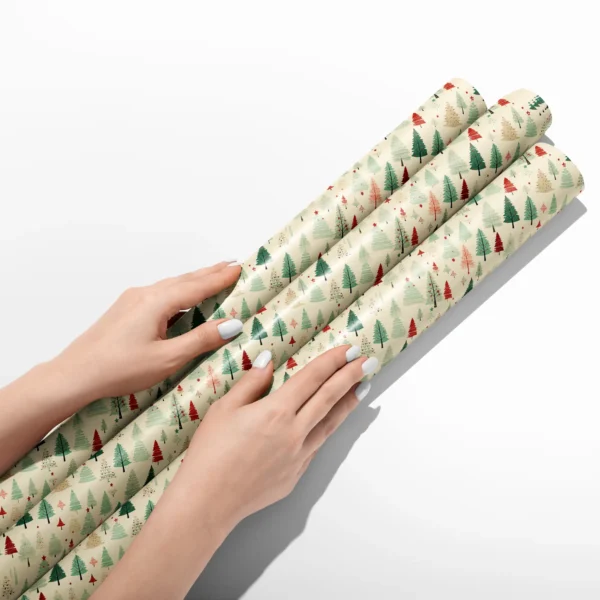 Hands smoothing three rolls of cream vintage forest wrapping paper on a white table