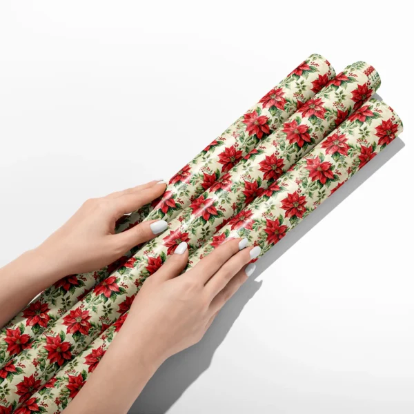 Hands smoothing three rolls of vintage poinsettia wrapping paper on a white table