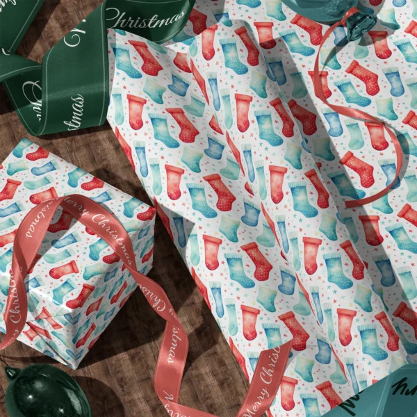 A sheet of watercolor stocking gift wrap and a wrapped box with satin ribbons on a wooden floor