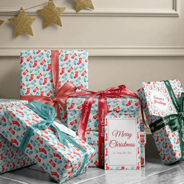 Stack of presents in watercolor stocking paper with ribbons and a Merry Christmas card by a beige wall