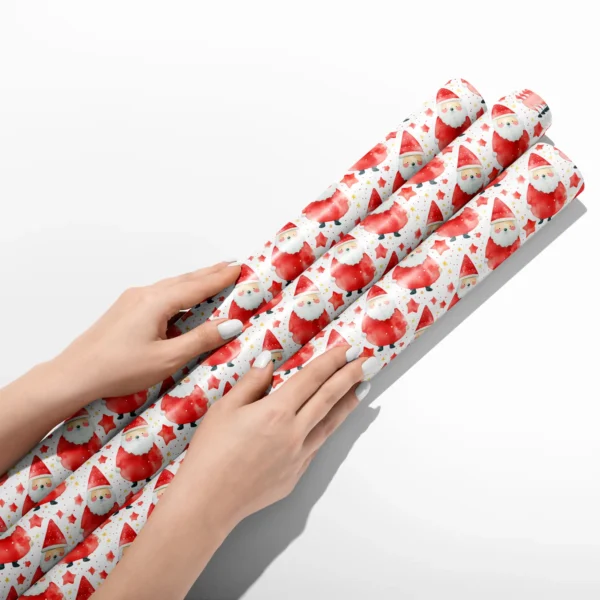 Hands smoothing three rolls of red watercolor Santa wrapping paper on a white table