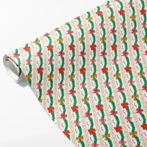 Roll of white wrapping paper with wavy green garlands and plaid, gold and pink bows, partly unrolled on white