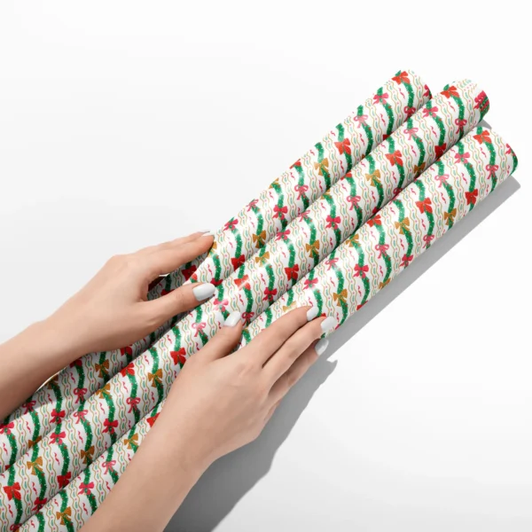 Hands smoothing three rolls of wavy garland wrapping paper on a white table