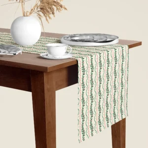 Winding berry vine Christmas table runner hanging over the end of a walnut dining table, close-up