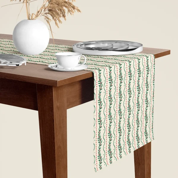 Winding berry vine Christmas table runner hanging over the end of a walnut dining table, close-up