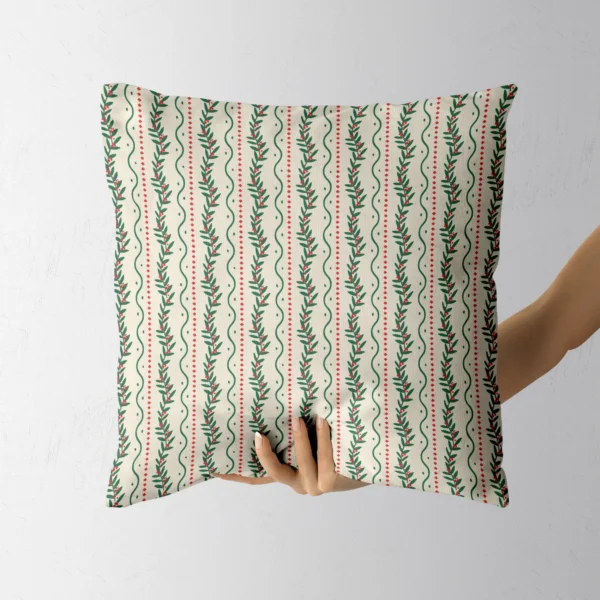 A hand holding the cream throw pillow with red berries and green waves