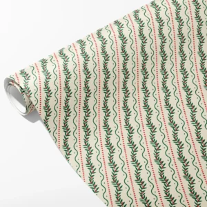 Roll of cream wrapping paper with winding green berry vines, wavy green lines and red dashes, partly unrolled on white
