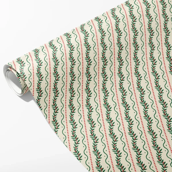 Roll of cream wrapping paper with winding green berry vines, wavy green lines and red dashes, partly unrolled on white