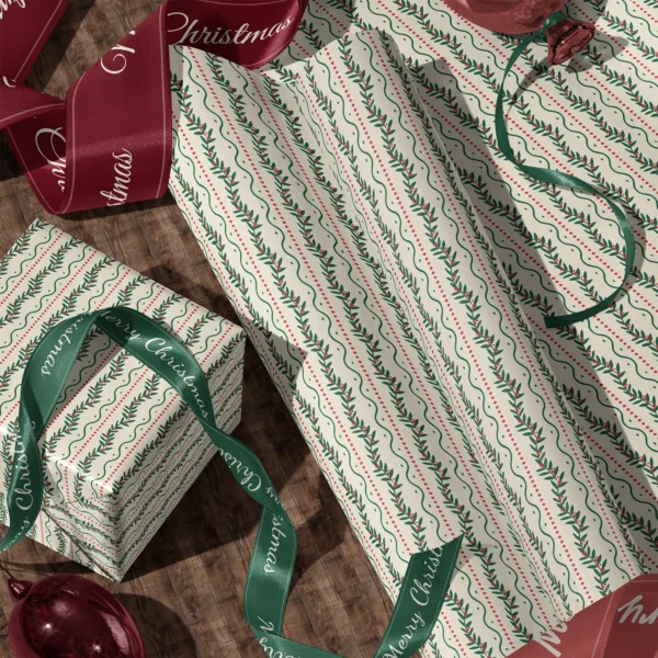 Rolls of berry vine gift wrap and a wrapped box with satin ribbons on a wooden floor