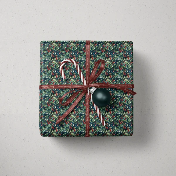 Top view of a gift in navy winter berry paper with a ribbon, a candy cane and a bauble