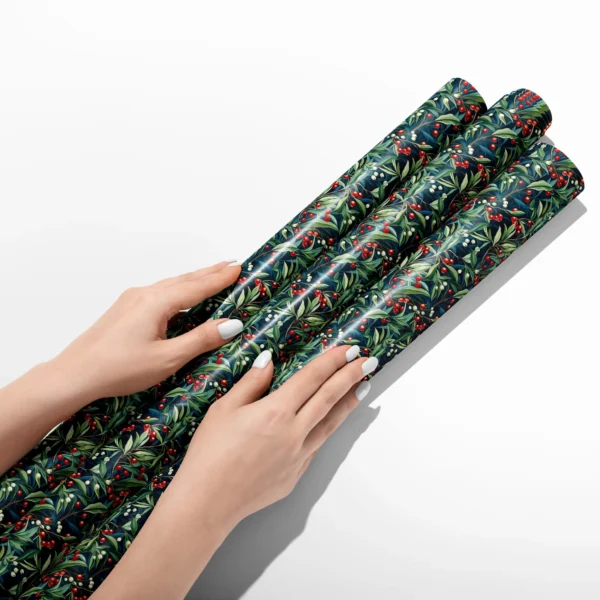 Hands smoothing three rolls of navy winter berry wrapping paper on a white table