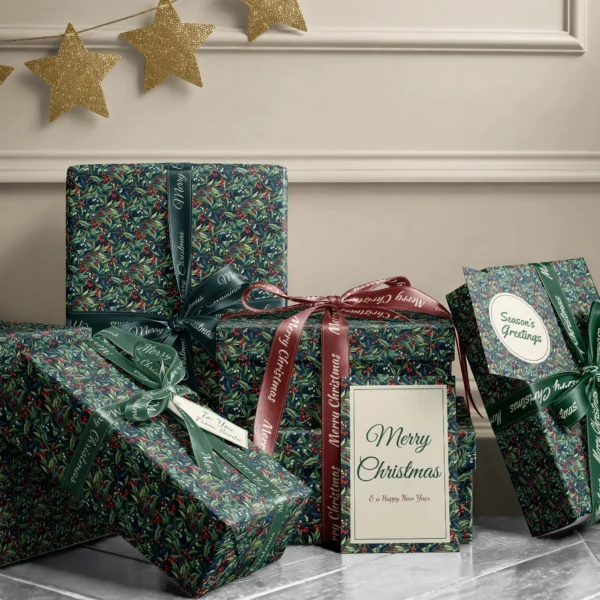 Stack of presents in navy winter berry paper with ribbons and a Merry Christmas card by a beige wall