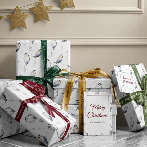 Stack of presents in white watercolor owl paper with ribbons and a Merry Christmas card by a beige wall