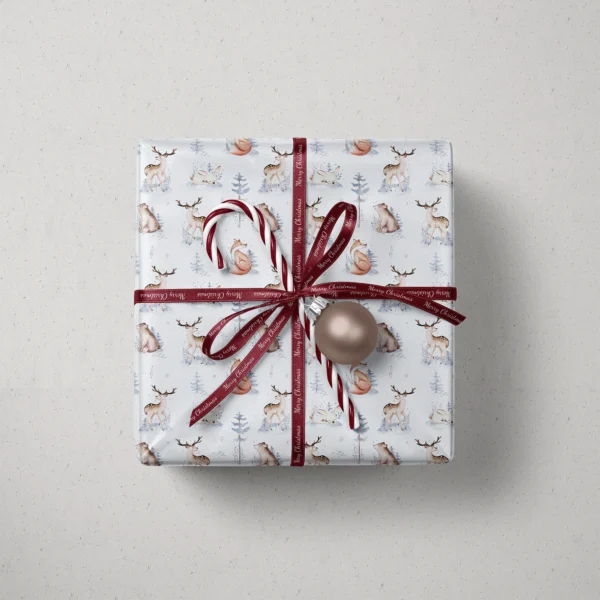 Top view of a gift in pale blue woodland paper with a ribbon, a candy cane and a bauble