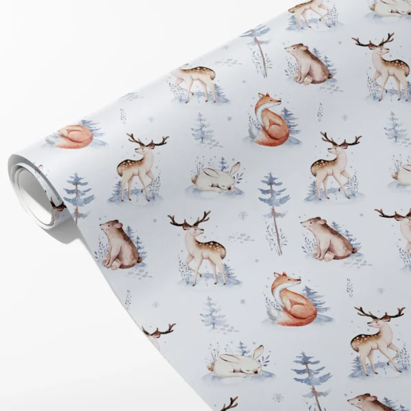 Roll of pale blue wrapping paper with watercolor deer, foxes, bears and rabbits among snowy firs, partly unrolled on white